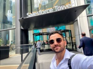 man wearing glasses standing in front of Salesforce Towers Sydney, smiling